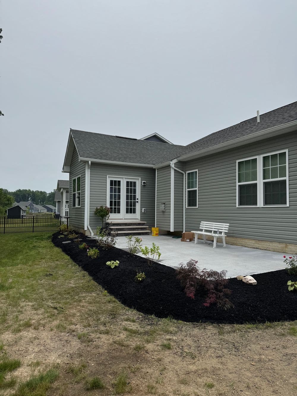 Newly constructed gray house with landscaped yard and concrete patio. Modern architecture details.