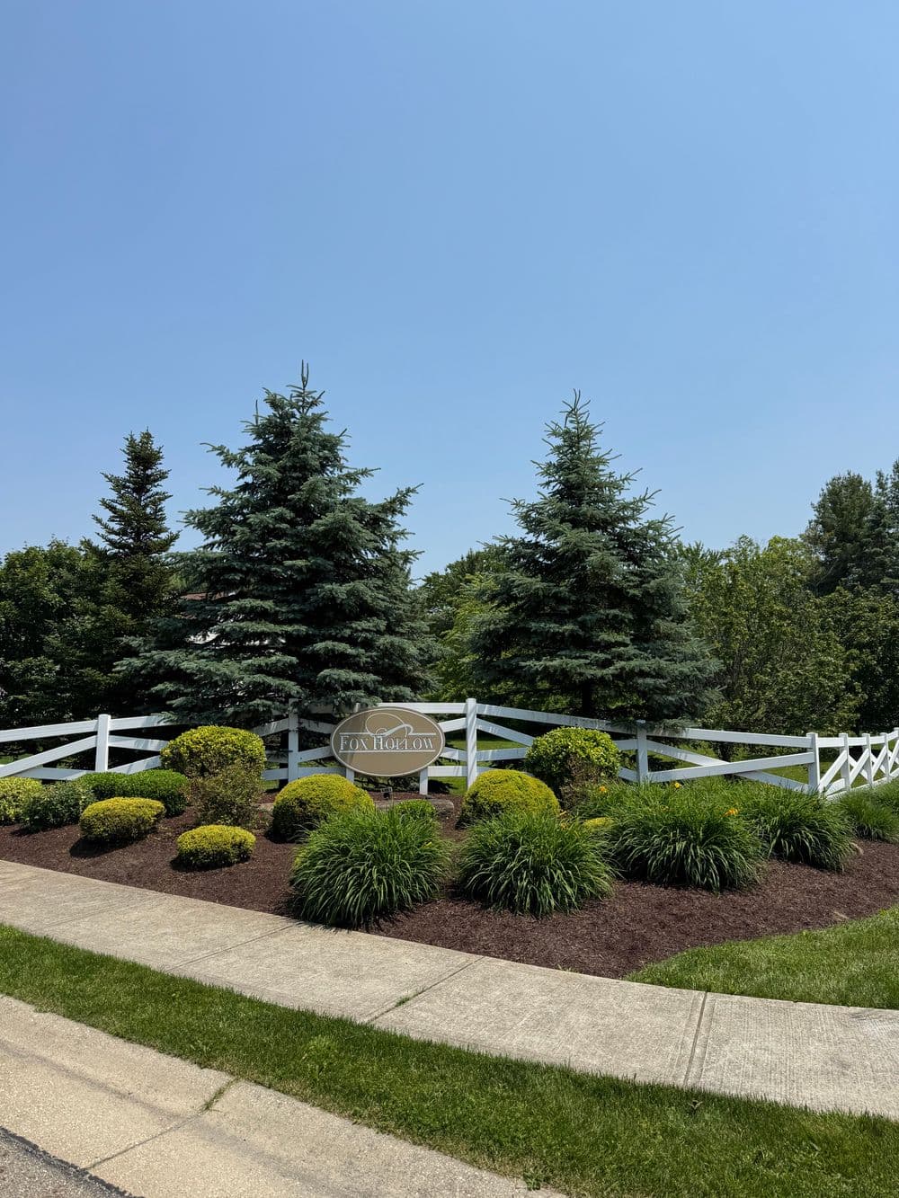 Entrance to Fox Hollow community with landscaped greenery and a white picket fence.