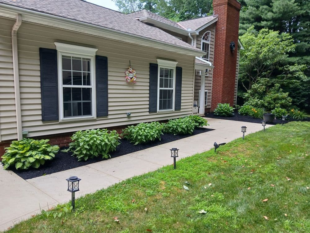 Charming home exterior with landscaped garden, black mulch, and garden lights.