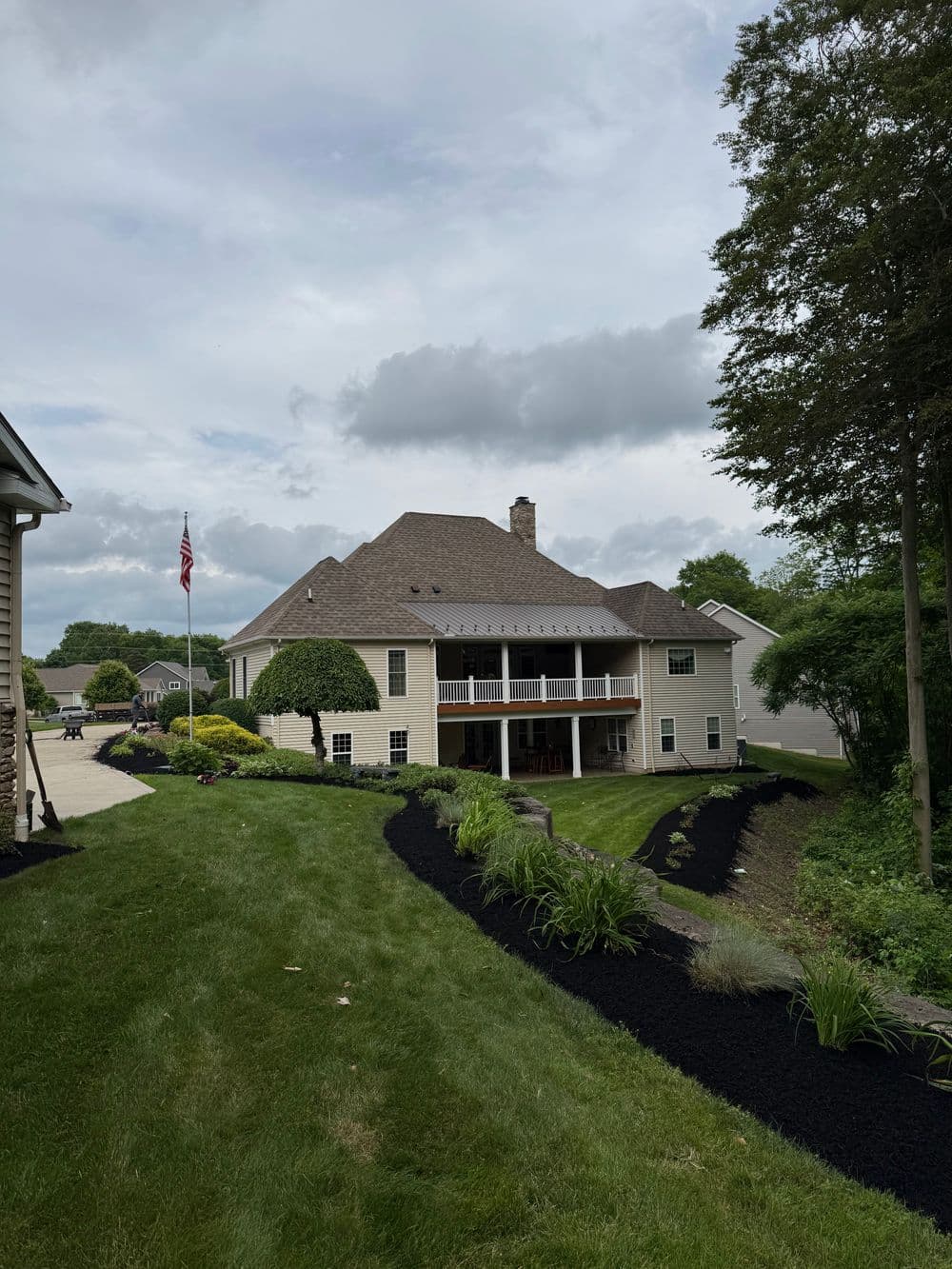 Modern two-story house with a spacious yard, featuring landscaping and a flagpole.
