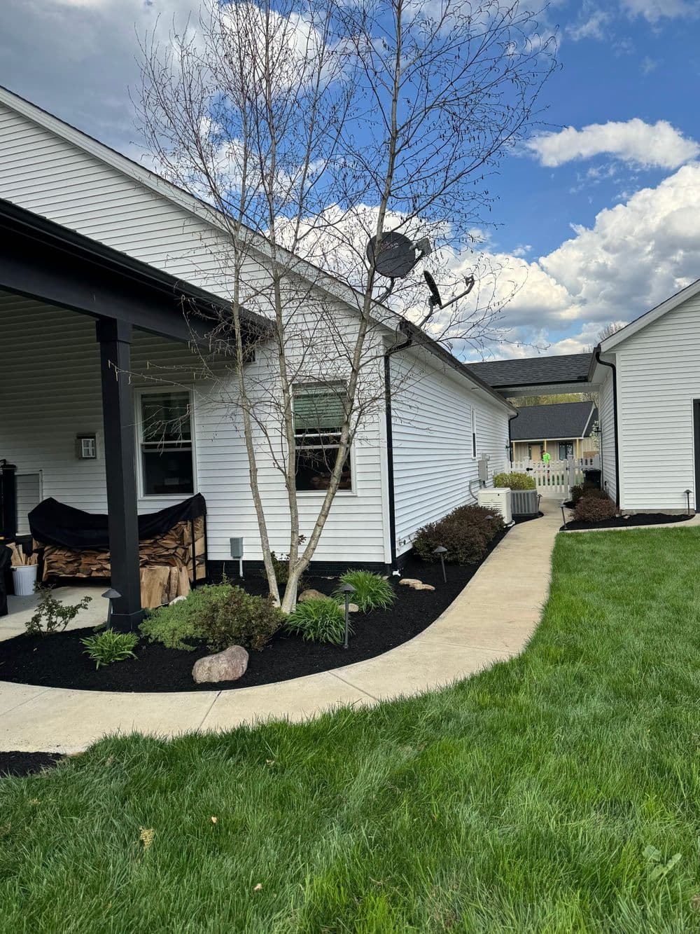 Modern white house exterior with landscaped lawn and pathway under a blue sky.