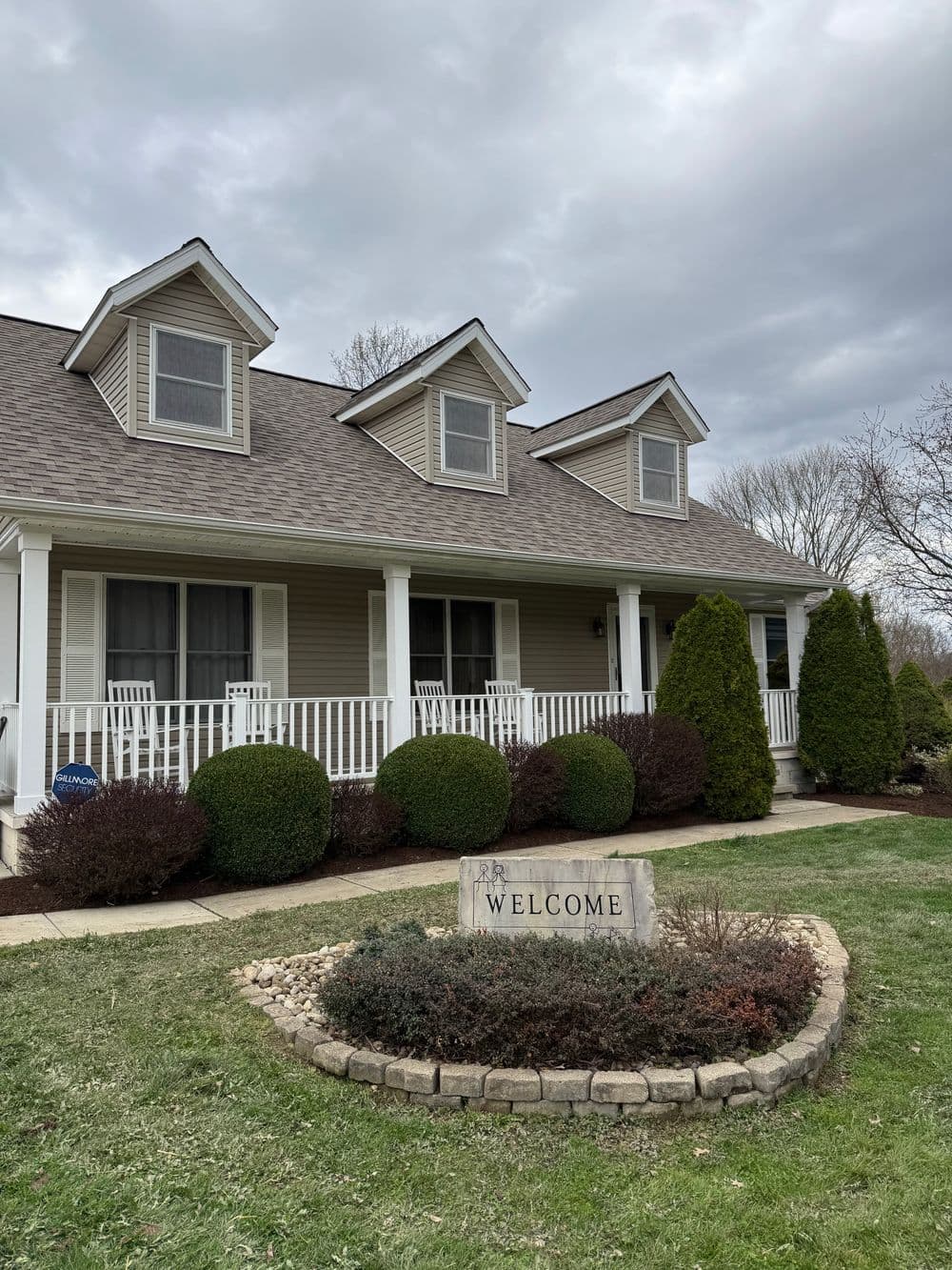 Charming beige house with a welcoming front porch and landscaped garden.