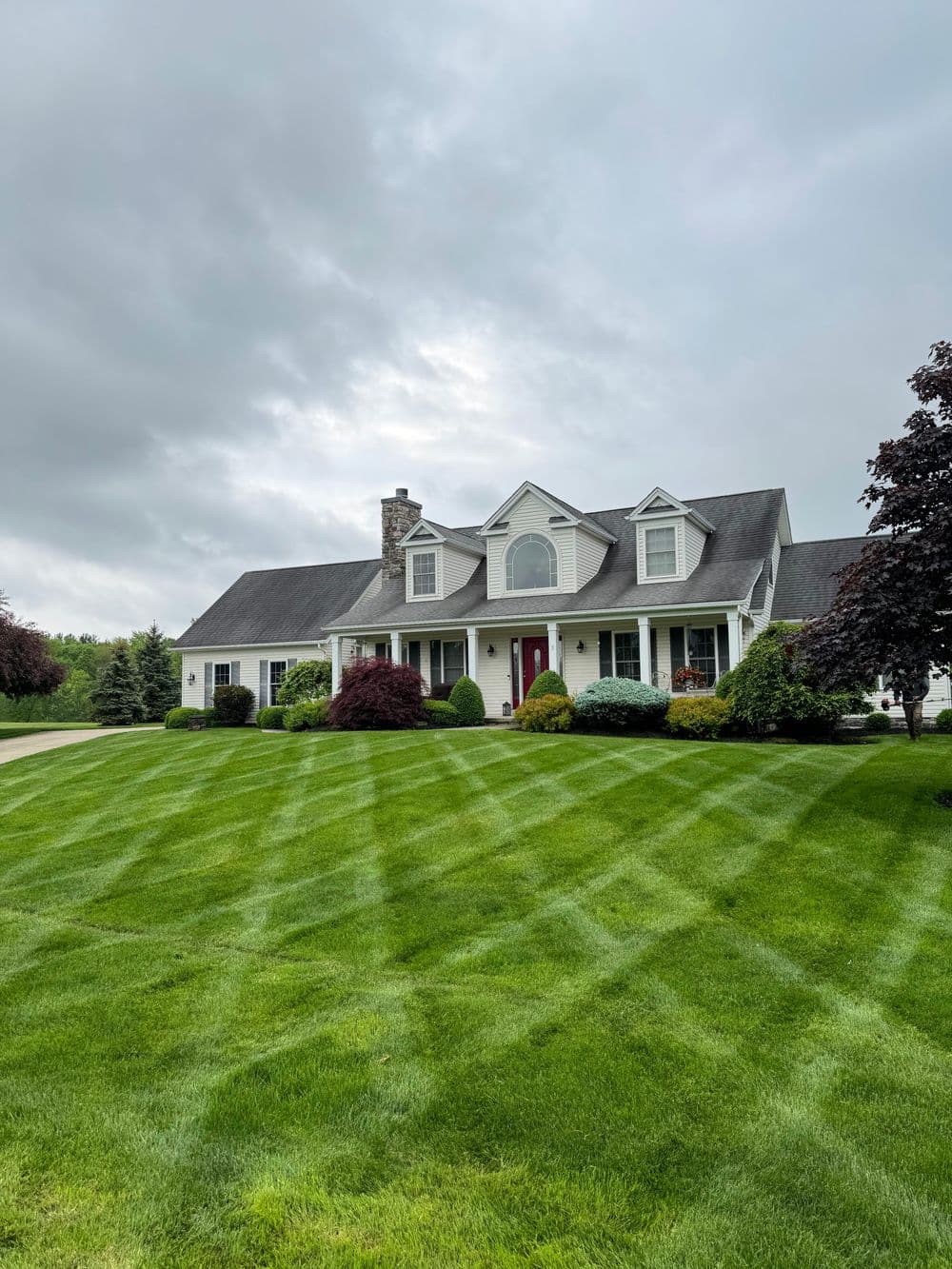 Charming home with manicured lawn and landscaped garden under a cloudy sky.