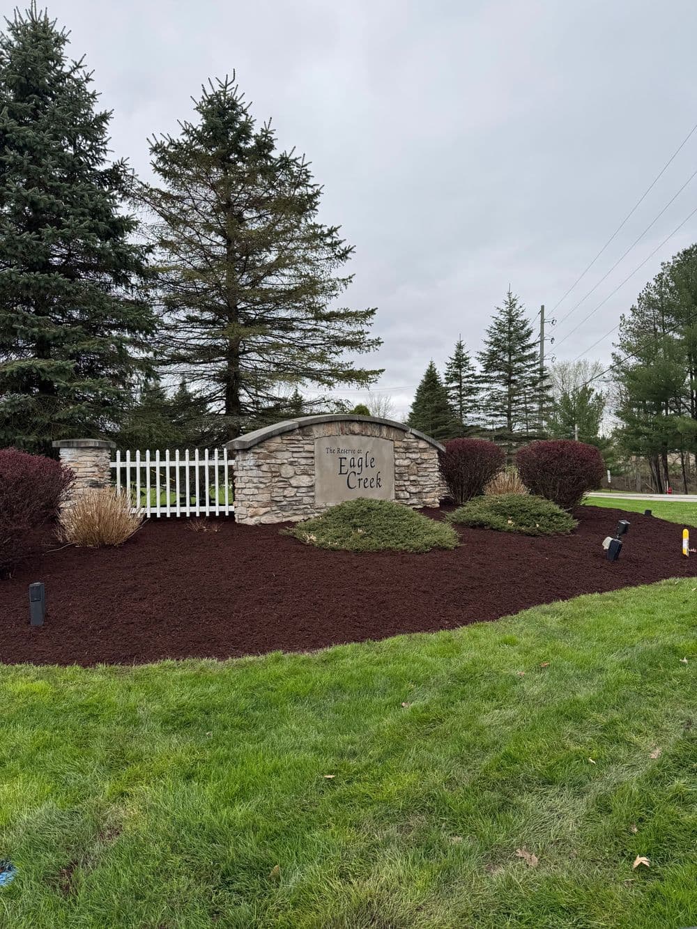 Eagle Creek entrance sign surrounded by landscaped greenery and decorative shrubs.