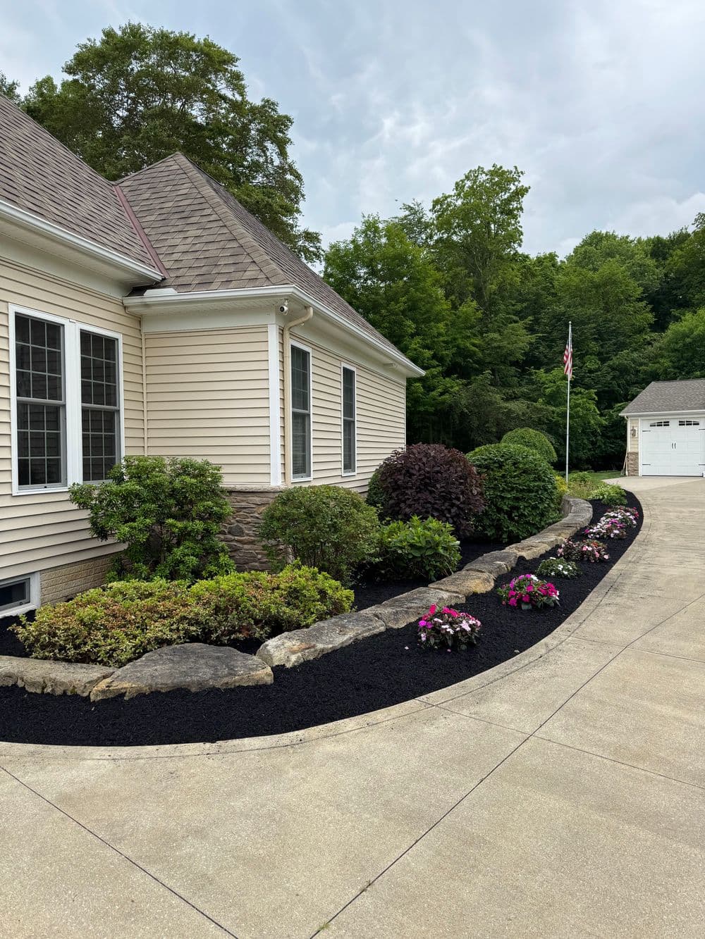 Beautiful suburban home exterior with landscaped garden, black mulch, and colorful flowers.